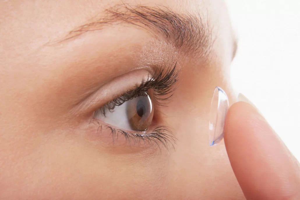 A woman puts a contact lens into her eye